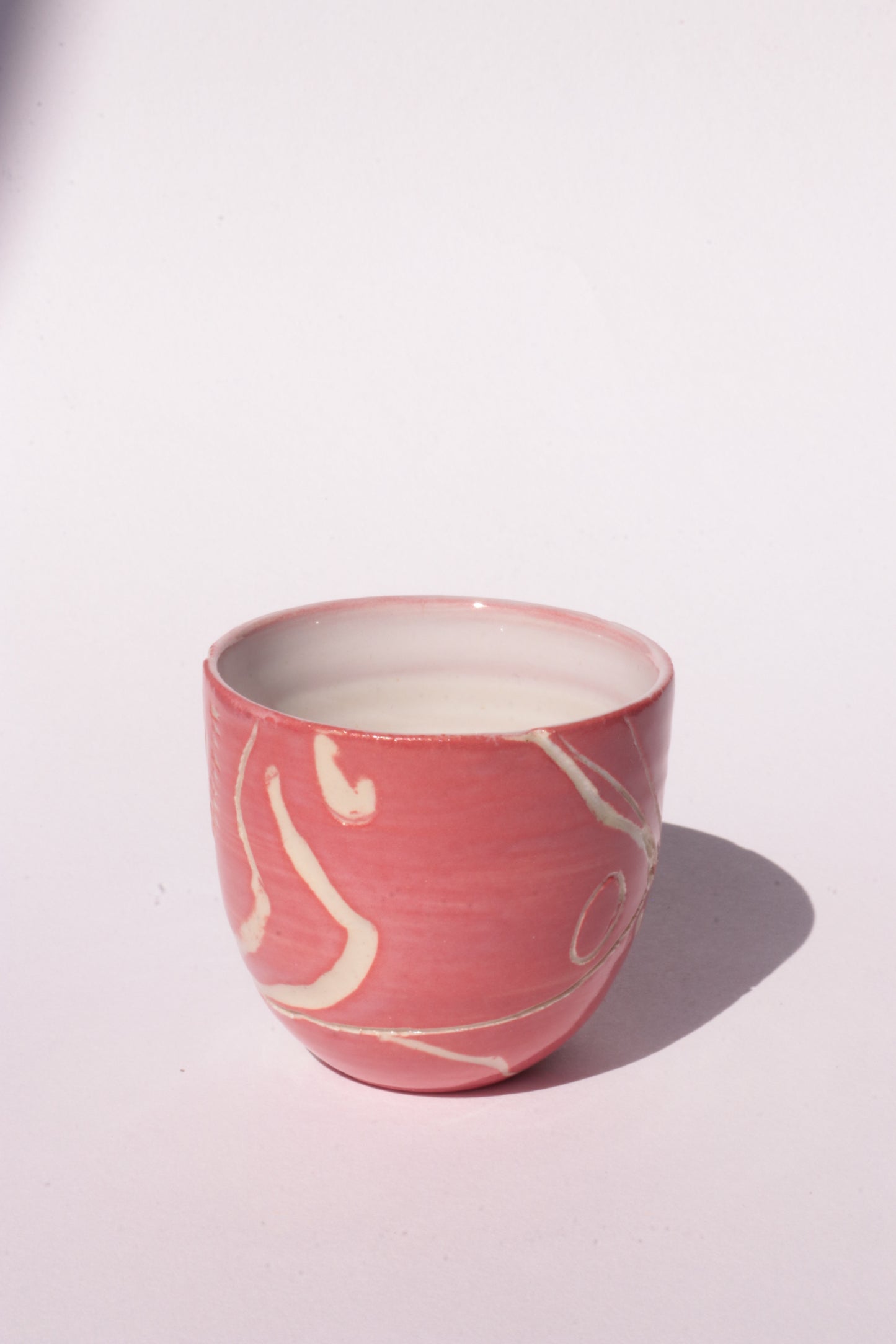 engraved magenta ceramic cup on white background
