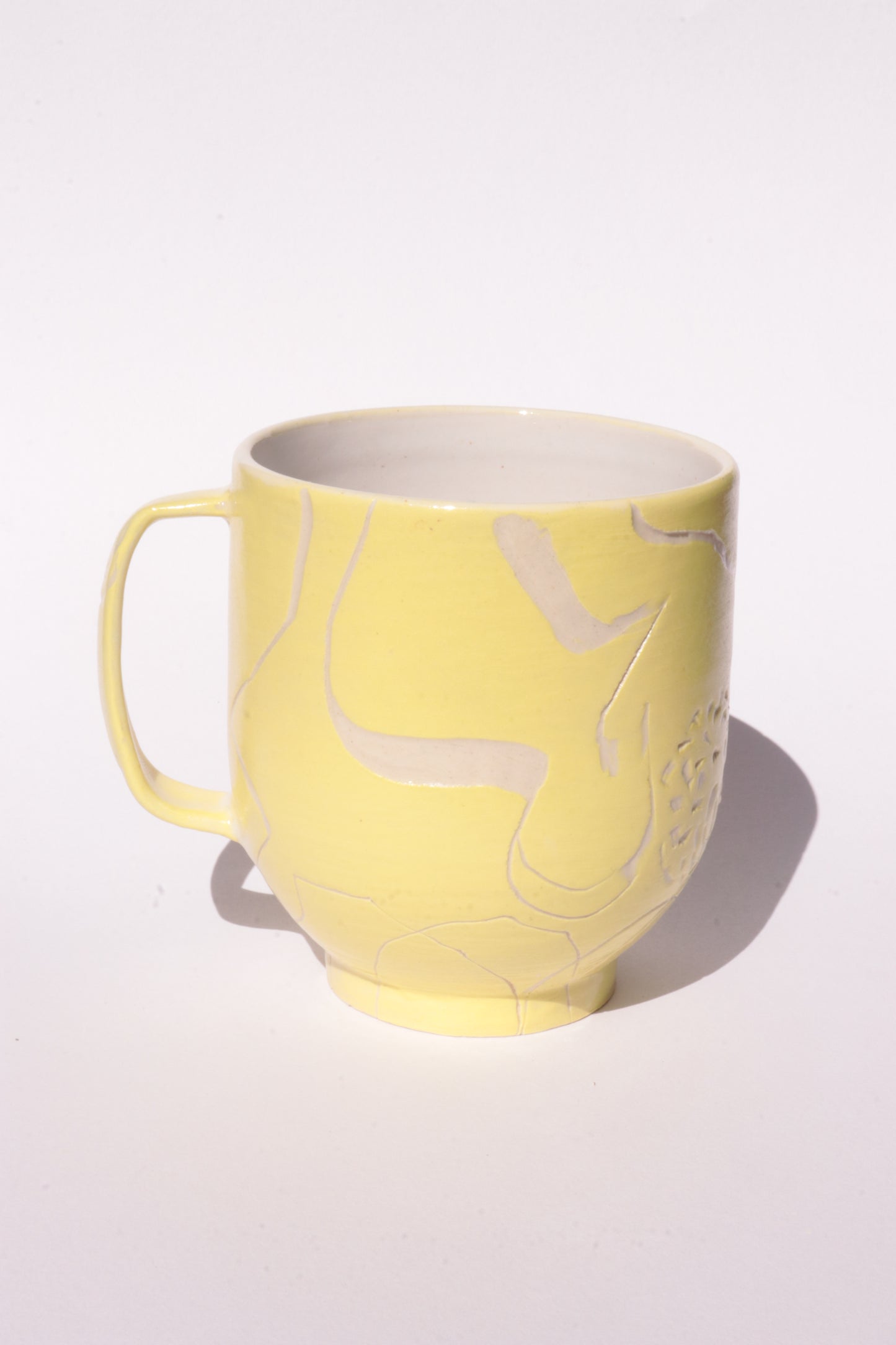 Yellow mug with engraved white abstract design on a white background