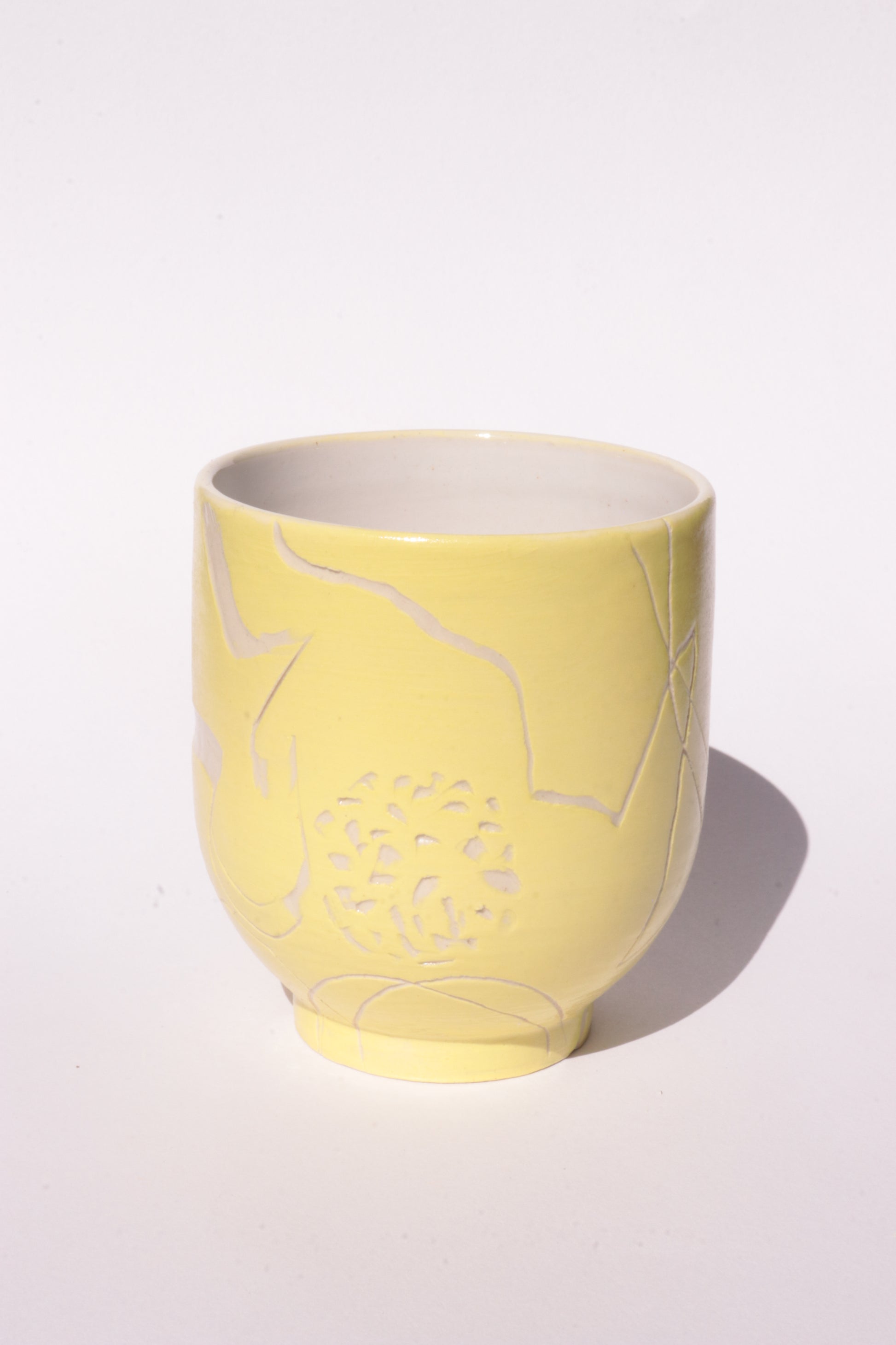 Yellow mug with engraved white abstract design on a white background