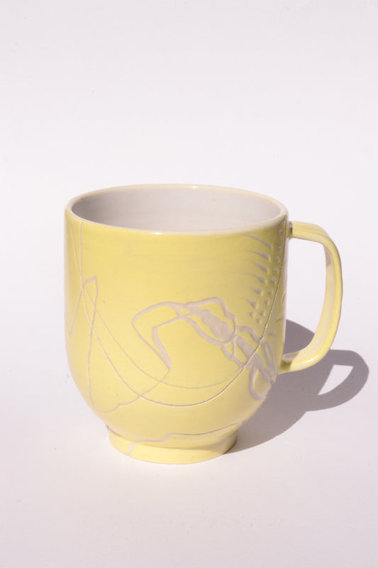 Yellow mug with engraved white abstract design on a white background