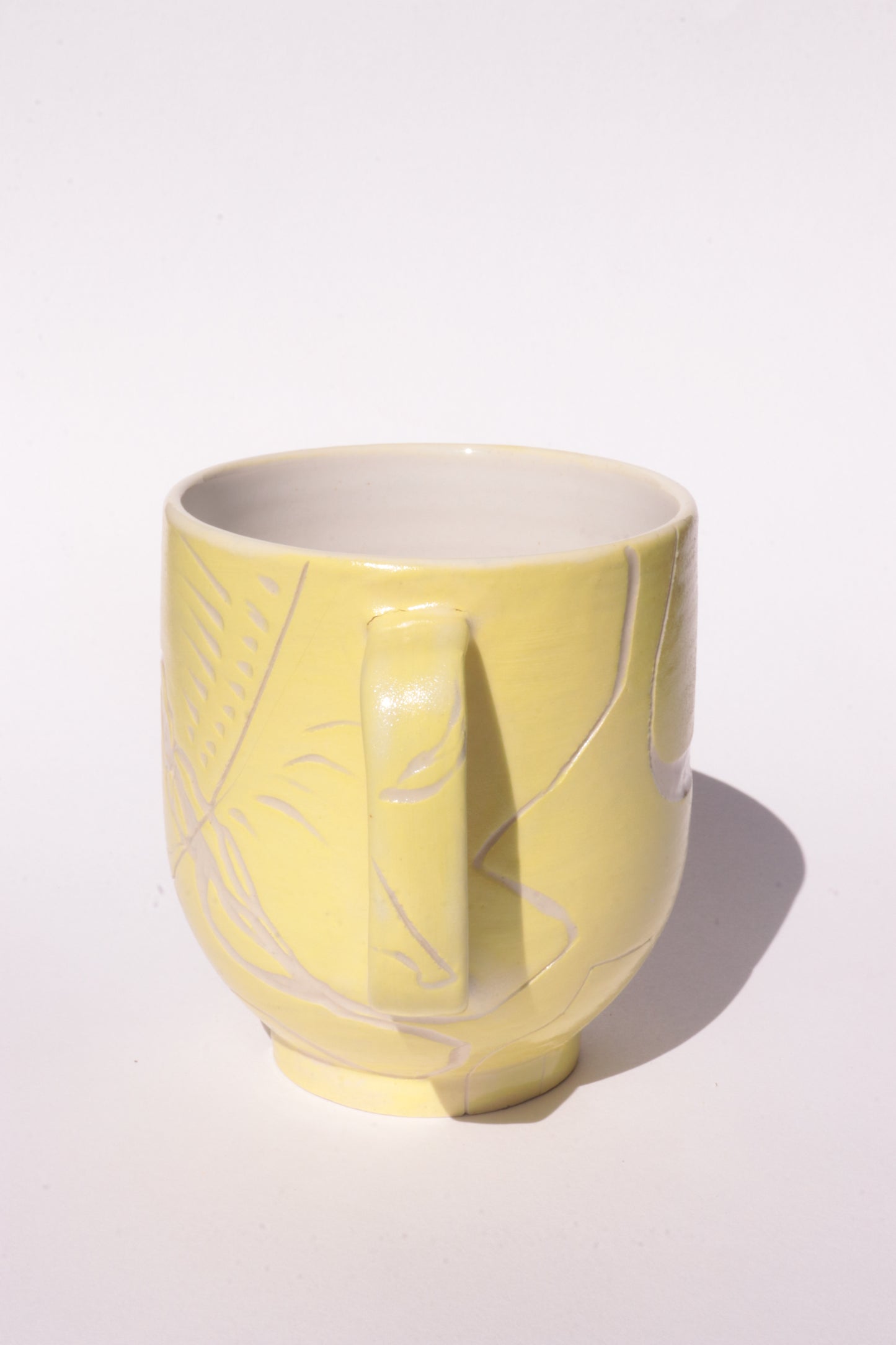 Yellow mug with engraved white abstract design on a white background