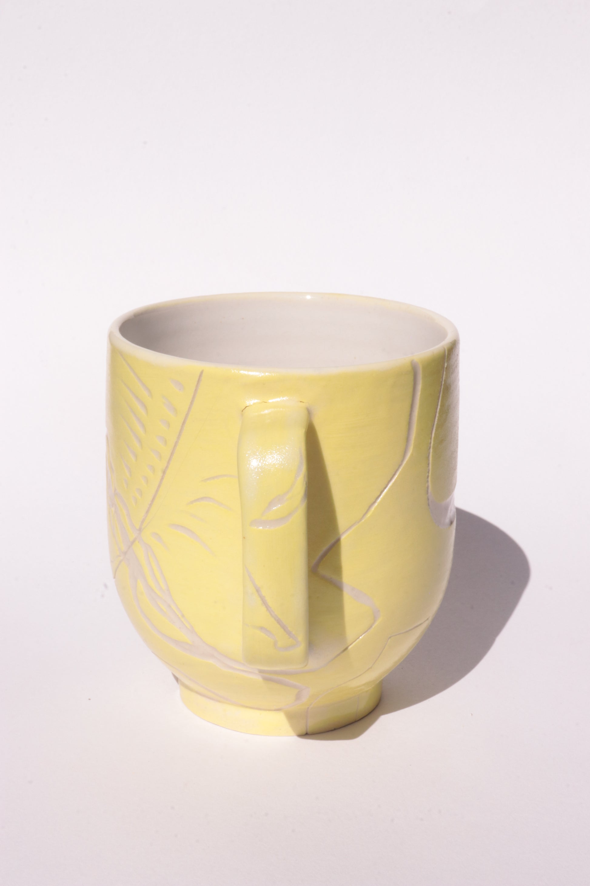 Yellow mug with engraved white abstract design on a white background