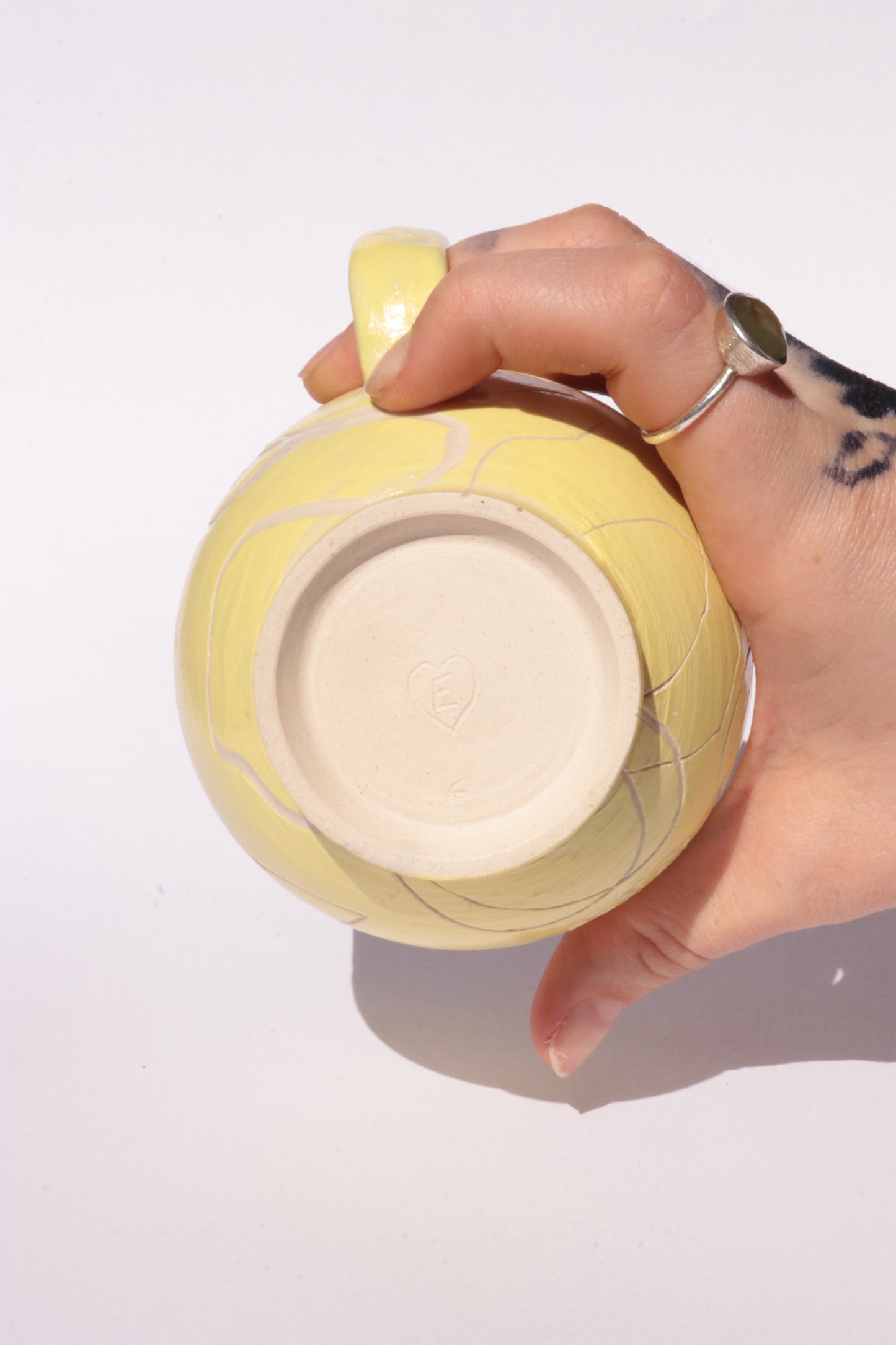 Yellow mug with engraved white abstract design on a white background
