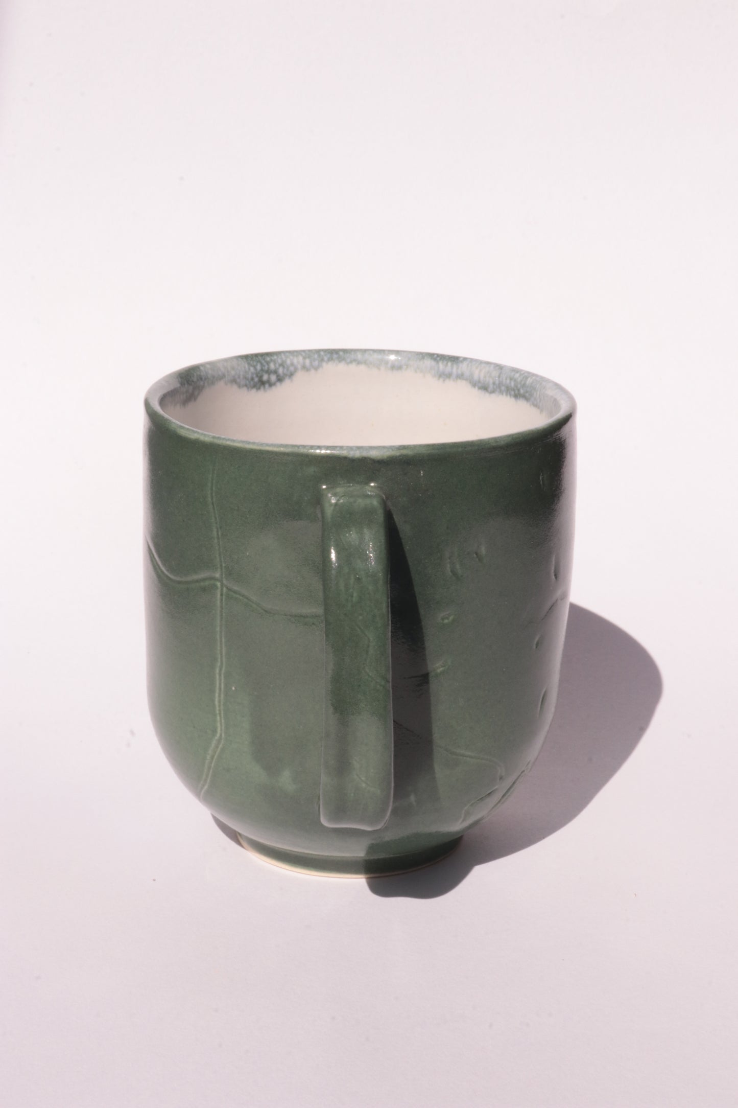 Dark green mug with engraved abstract design on a white background
