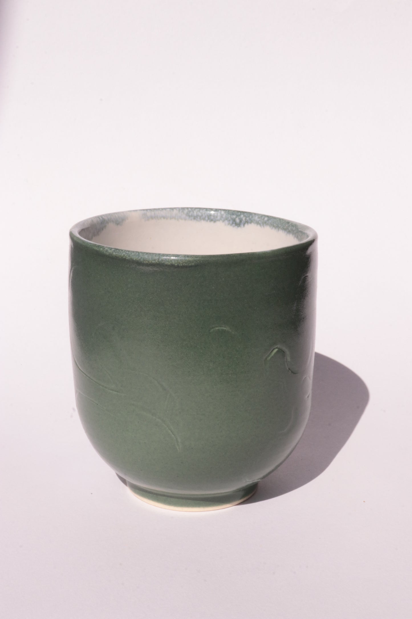 Dark green mug with engraved abstract design on a white background