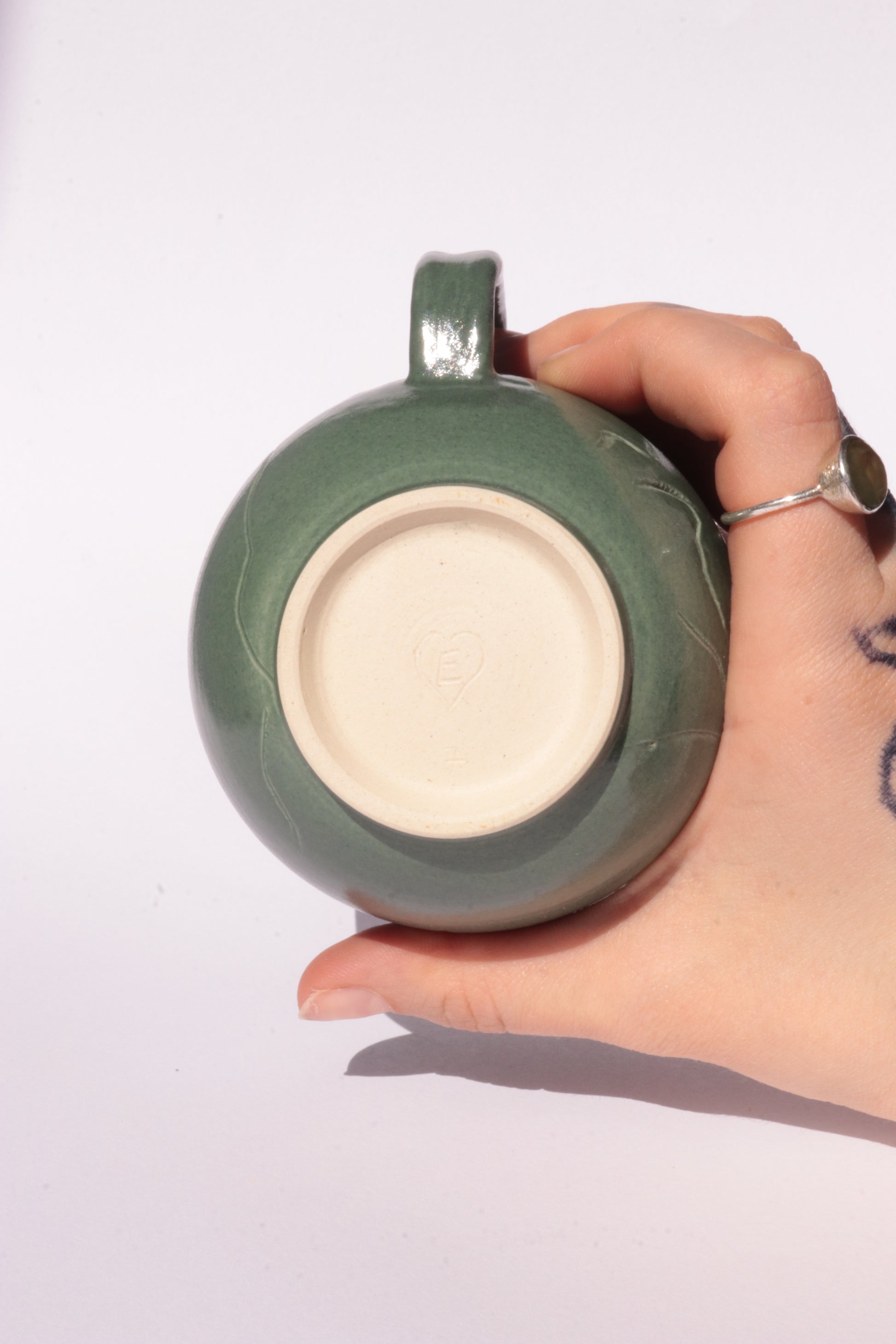 Dark green mug with engraved abstract design on a white background