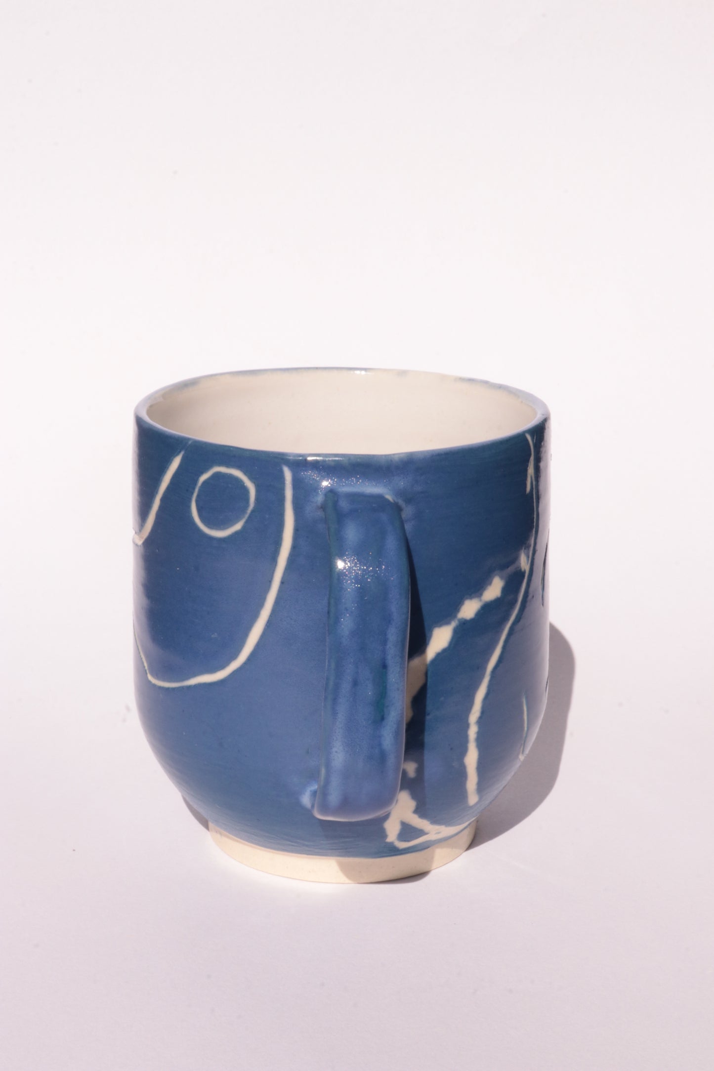 Blue mug with engraved white abstract design on a white background
