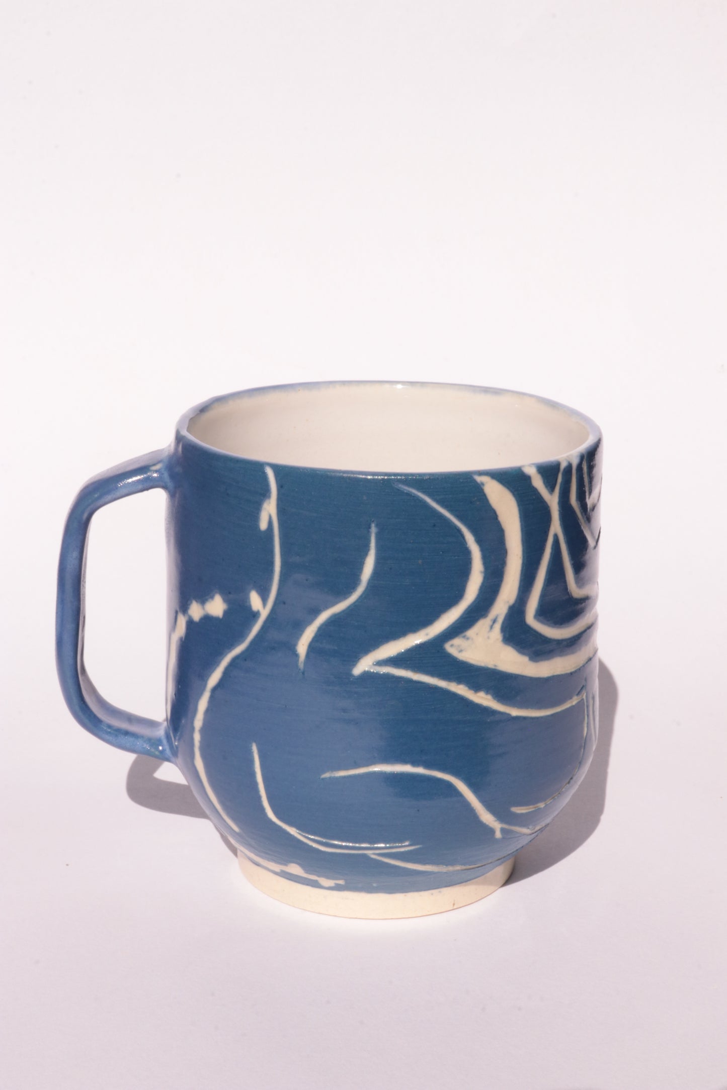 Blue mug with engraved white abstract design on a white background