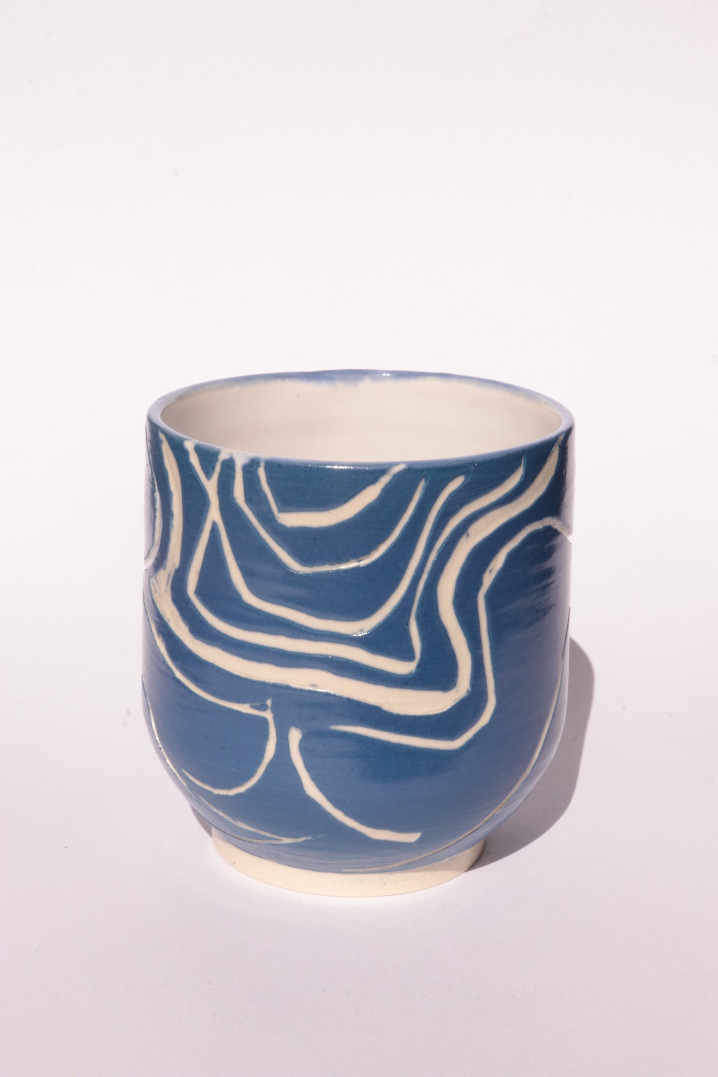 Blue mug with engraved white abstract design on a white background