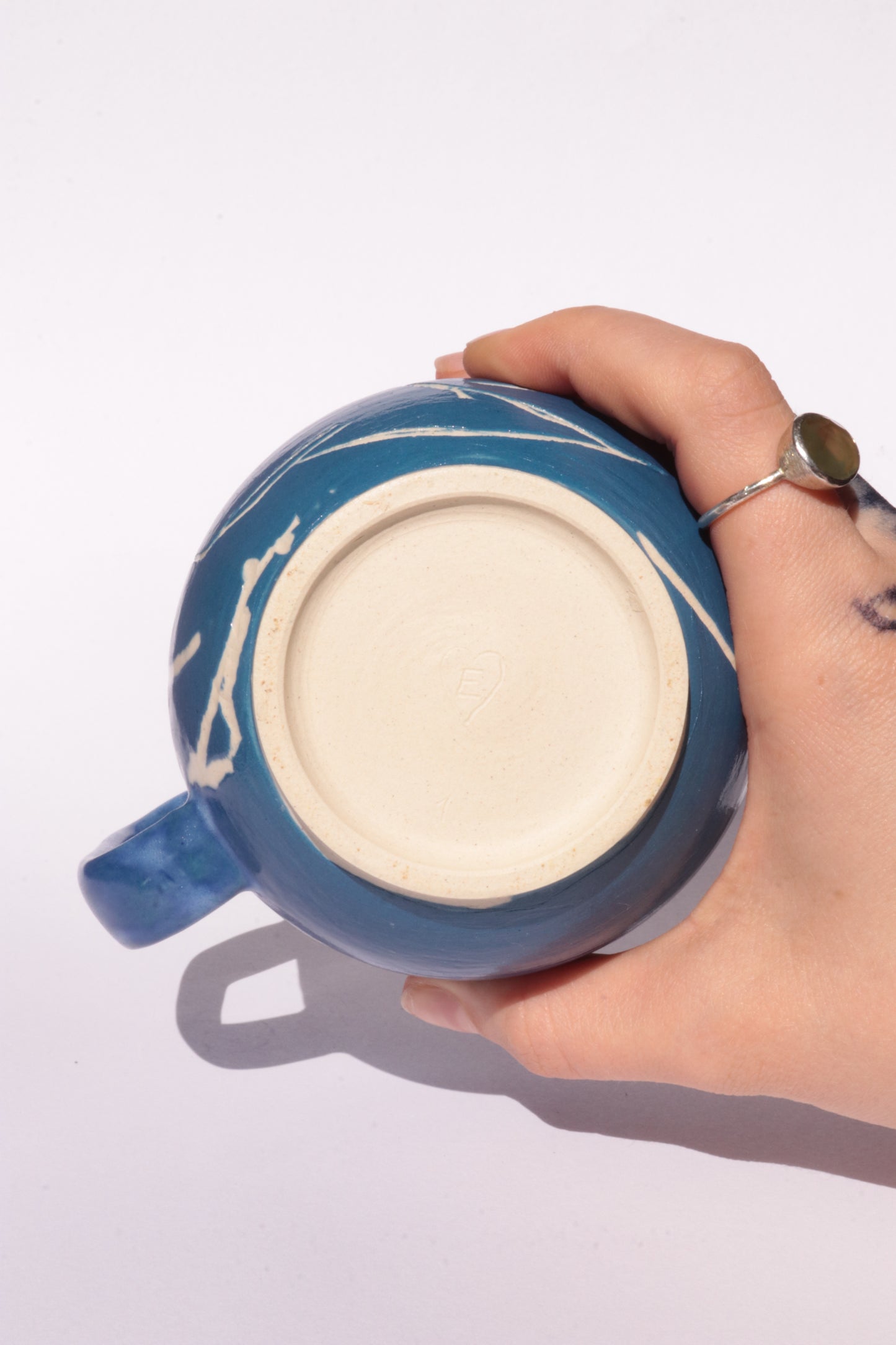 Blue mug with engraved white abstract design on a white background