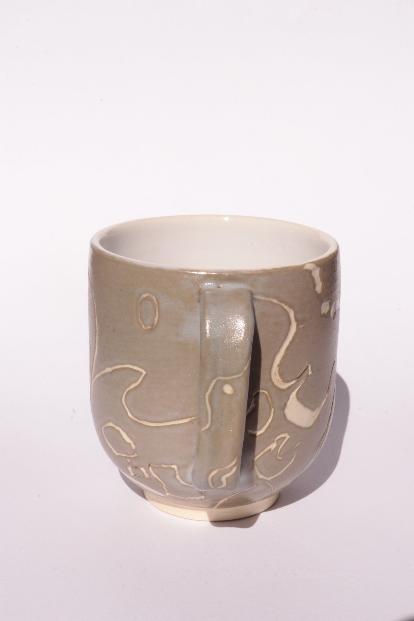Brown mug with engraved white abstract design on a white background