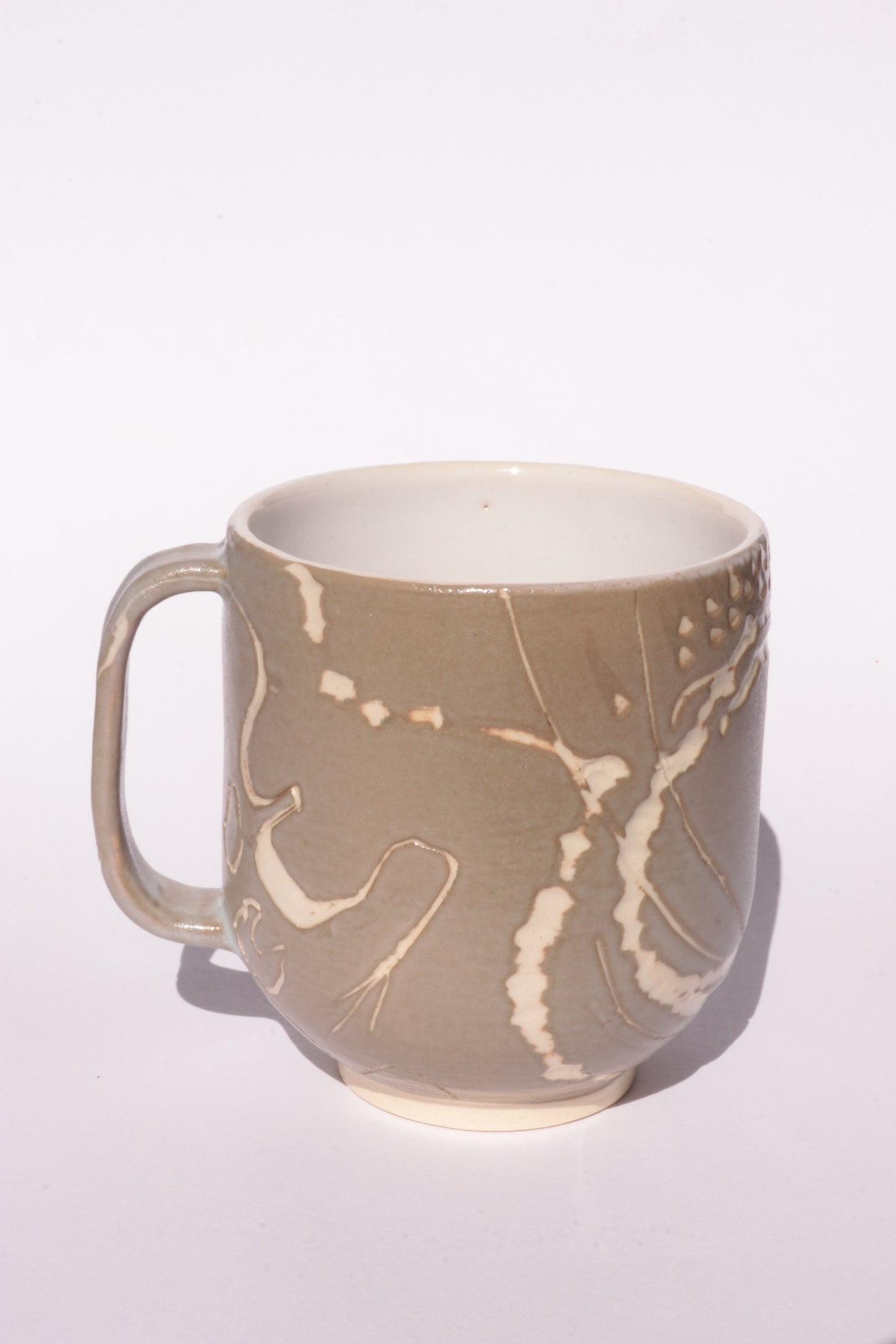Brown mug with engraved white abstract design on a white background