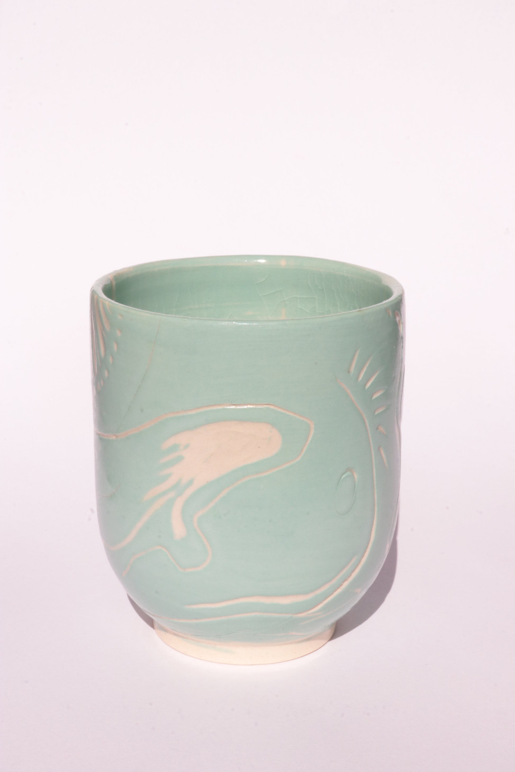 Teal mug with engraved white abstract design on a white background