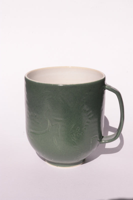 Dark green mug with subtle engraved design on a white background
