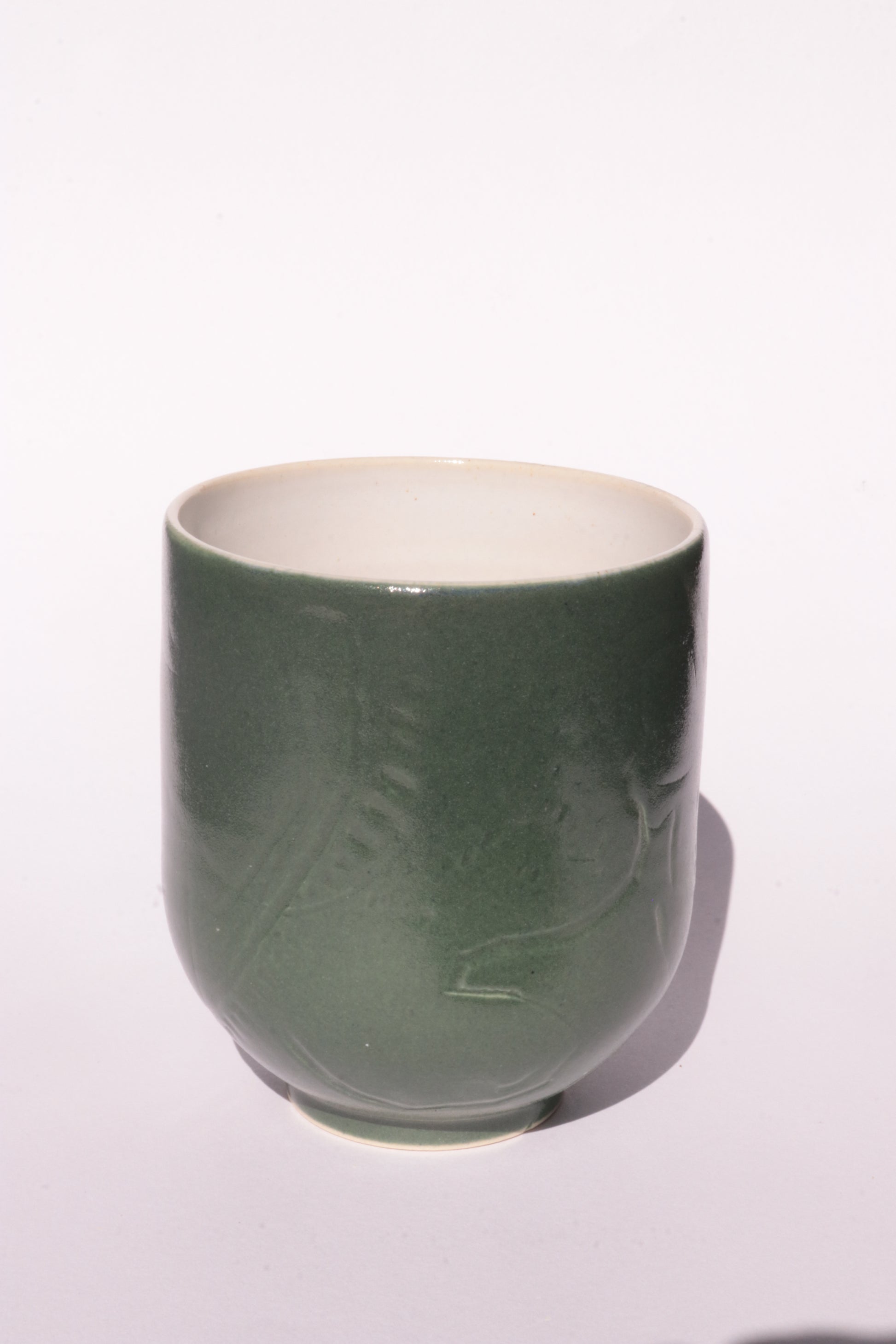 Dark green mug with subtle engraved design on a white background