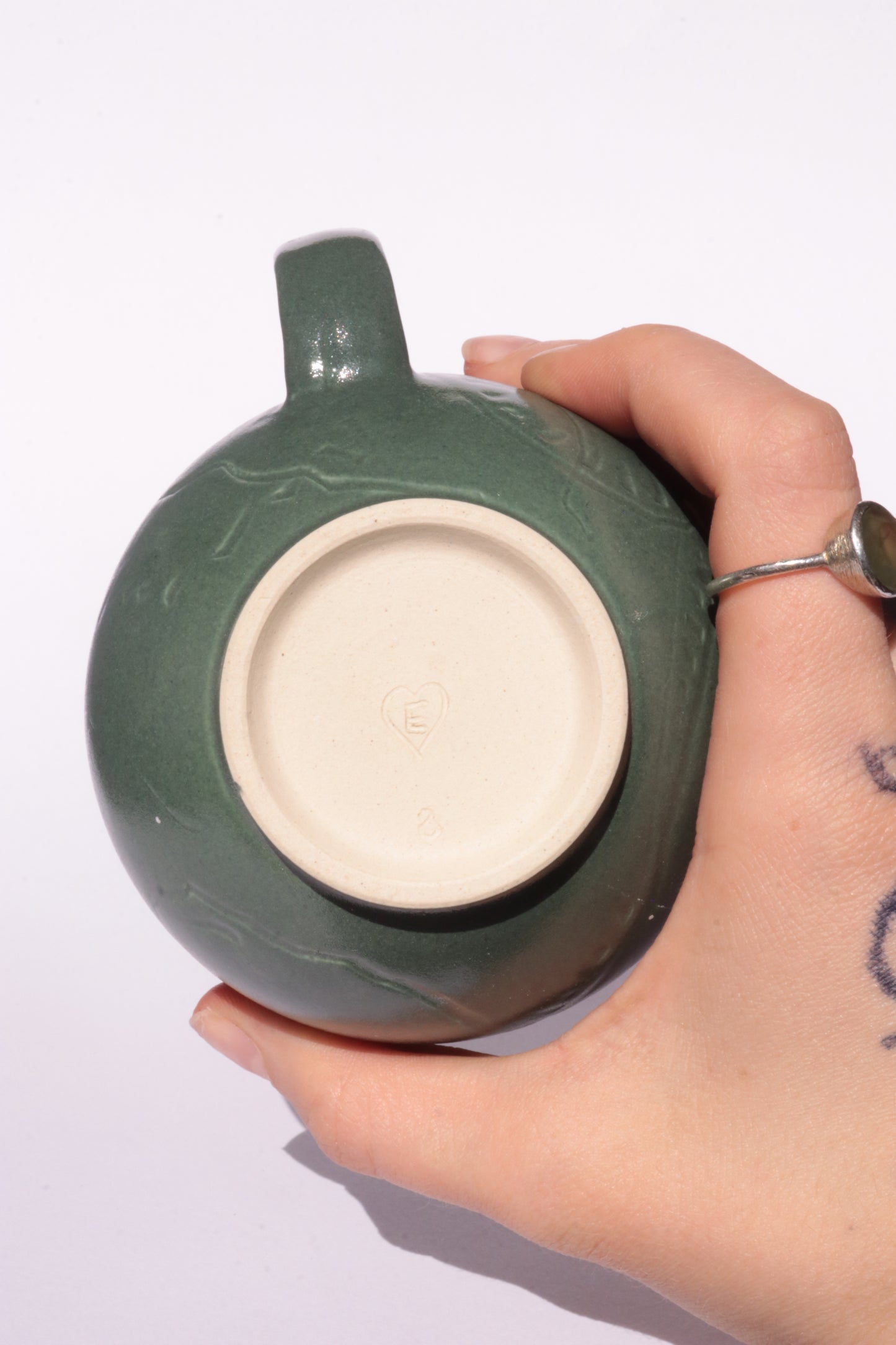 Dark green mug with subtle engraved design on a white background
