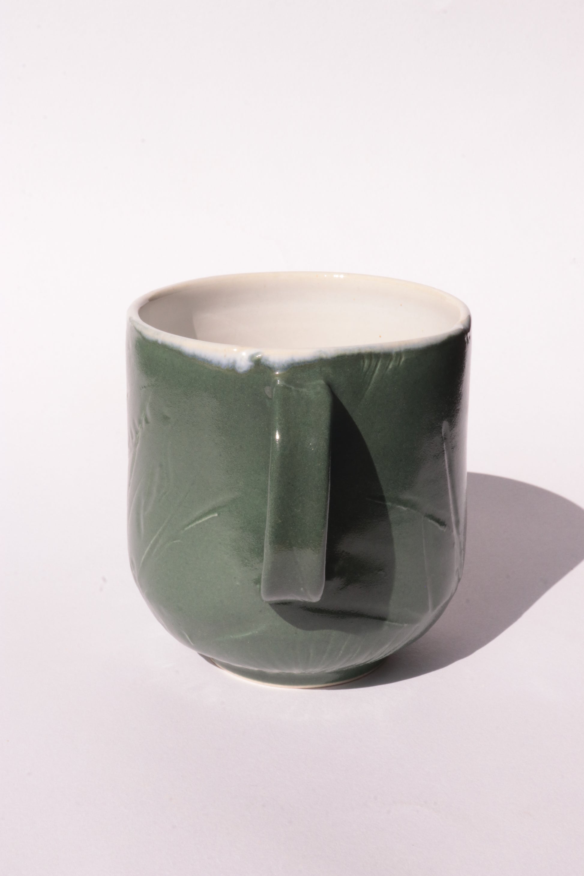 Dark green mug with subtle engraved design on a white background