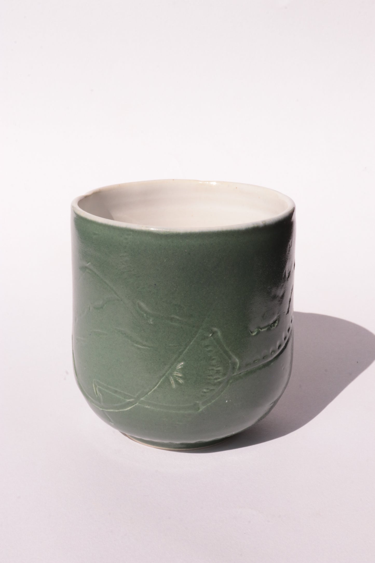 Dark green mug with subtle engraved design on a white background