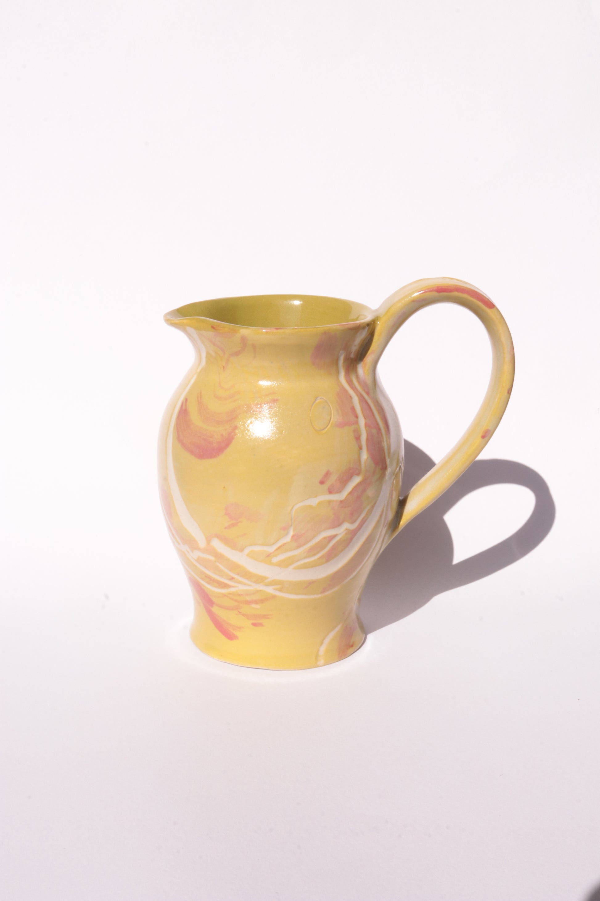 Ceramig jug with colourful engraved design on white background