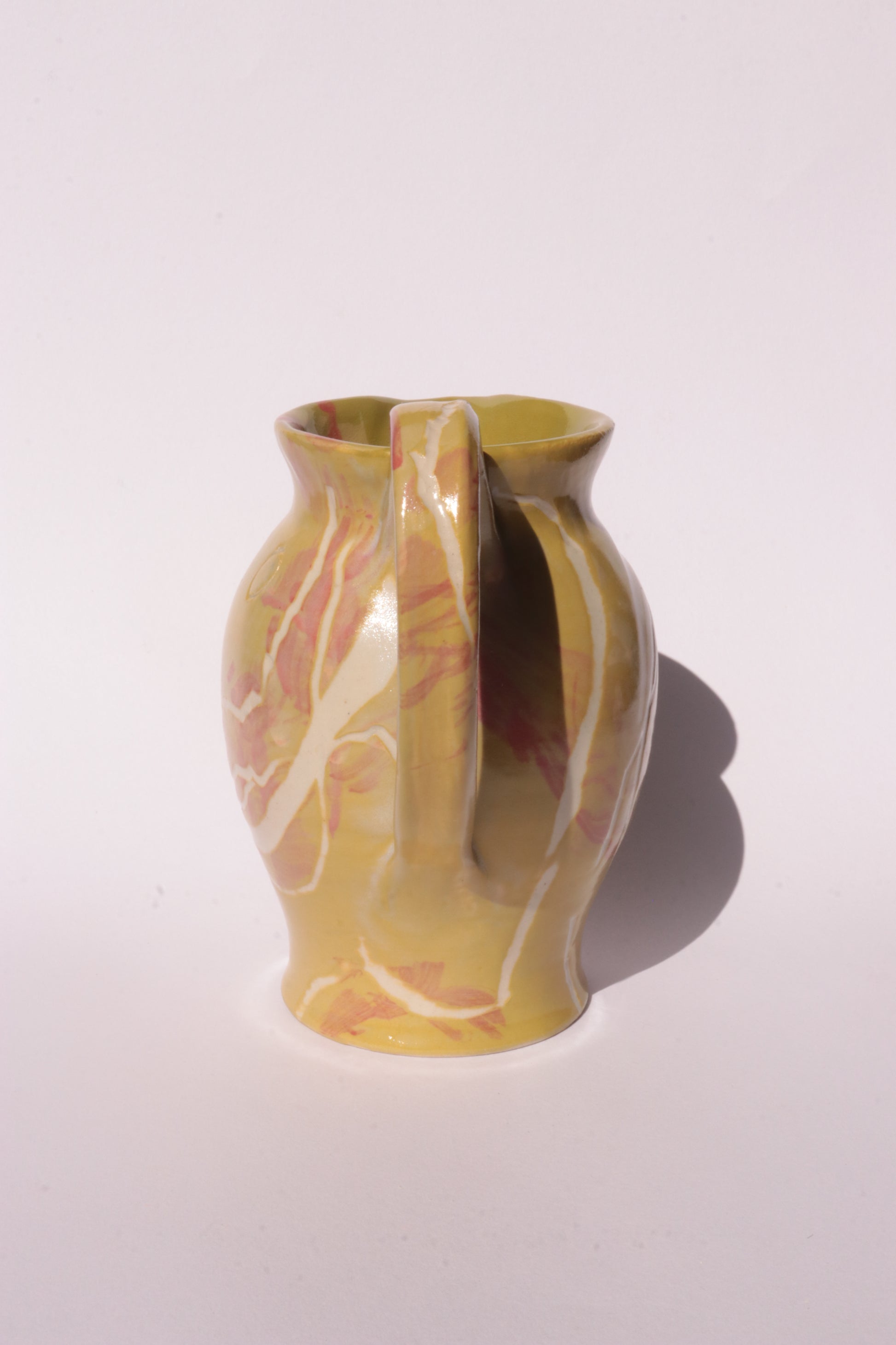 Ceramig jug with colourful engraved design on white background
