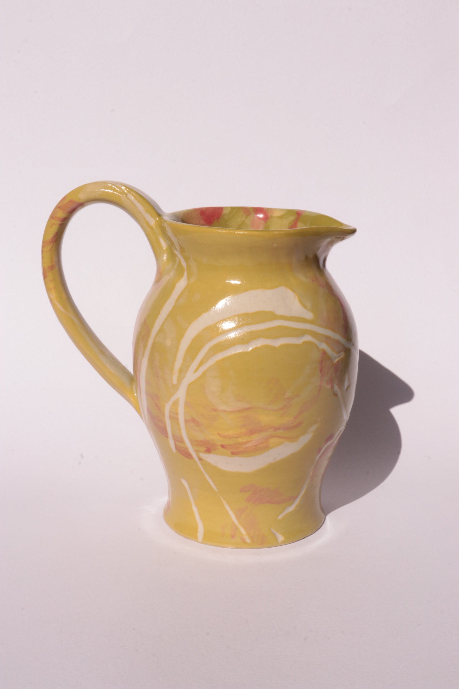 Ceramig jug with colourful engraved design on white background