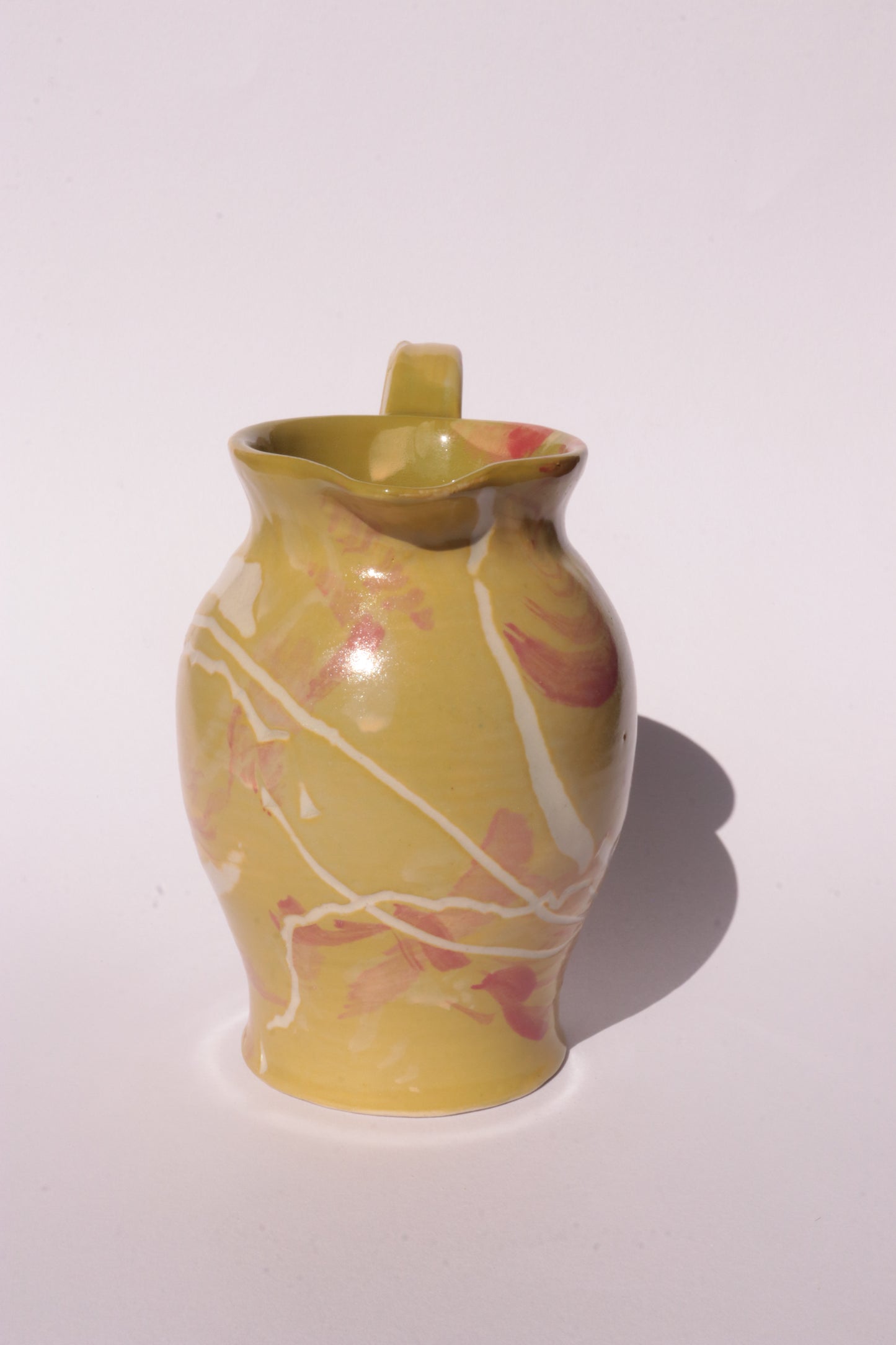 Ceramig jug with colourful engraved design on white background