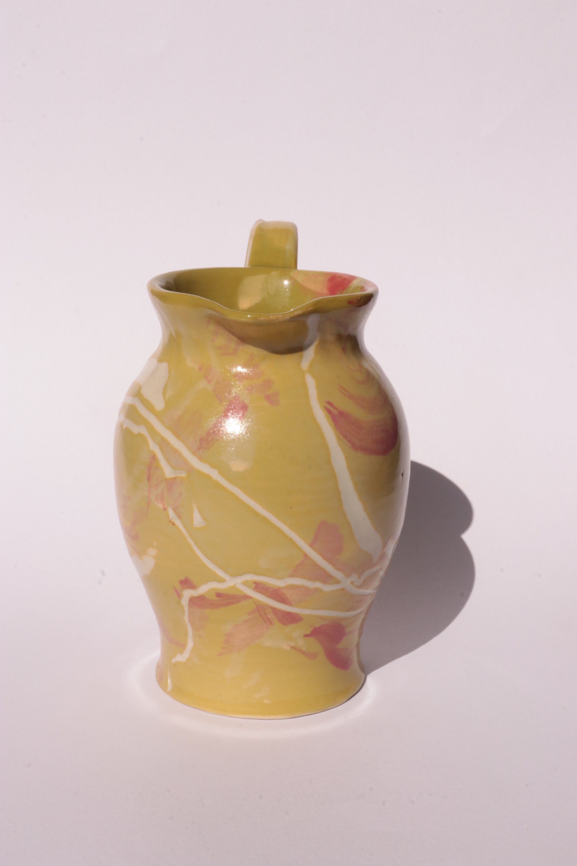 Ceramig jug with colourful engraved design on white background