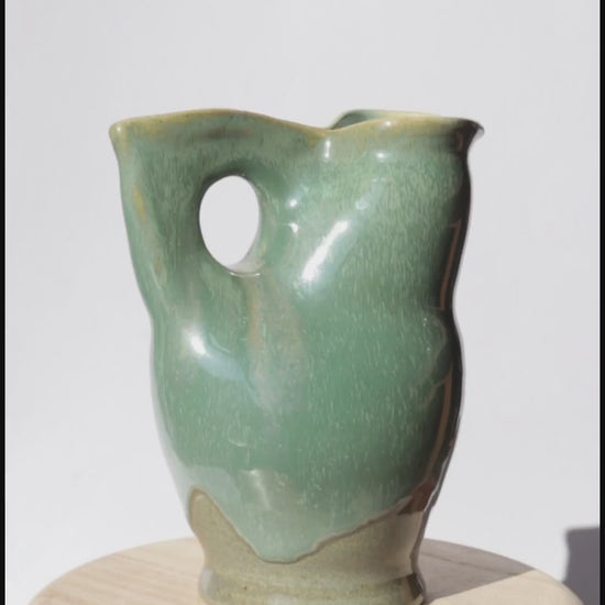 green ceramic jug spinning on itself against white background