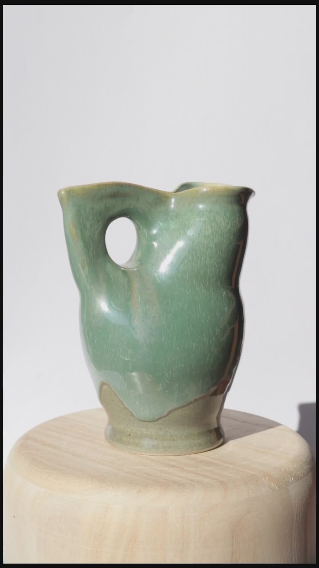 green ceramic jug spinning on itself against white background