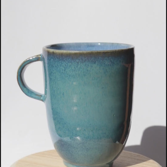 dark blue mug spinning on itself against white background